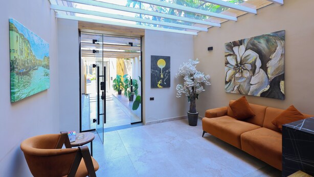 A modern interior with a sofa, a chair, a potted plant, and artwork on the walls. - Elite Boutique Hotel (New Cairo)