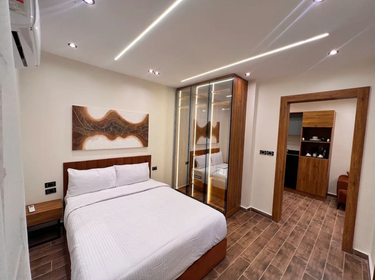 A bedroom with a bed, a wardrobe, and a bathroom visible through a glass door.