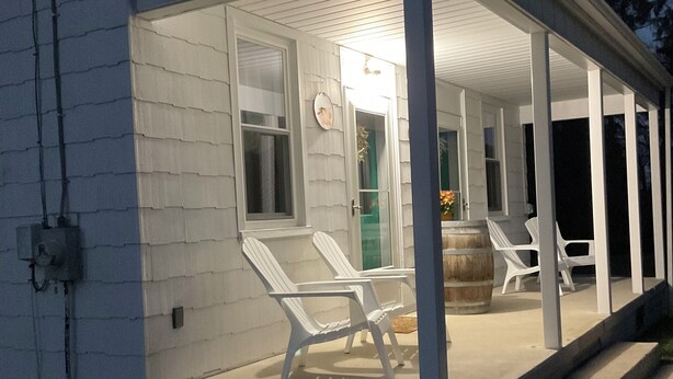 A covered porch with white chairs and a wooden barrel. - Charming 3-bedroom 2 bath farmhouse surrounded by Corodus State Park in Hanover. (Hanover)