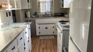 A modern kitchen with white cabinetry, a marble countertop, and a central island. - Charming 3-bedroom 2 bath farmhouse surrounded by Corodus State Park in Hanover. (Hanover)