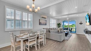 A spacious living area with a dining table, sofa, and a view of the outdoors. - Bayview Pointe! Luxury Villa near Anna Maria Island with Saltwater Heated Pool! (Cortez)
