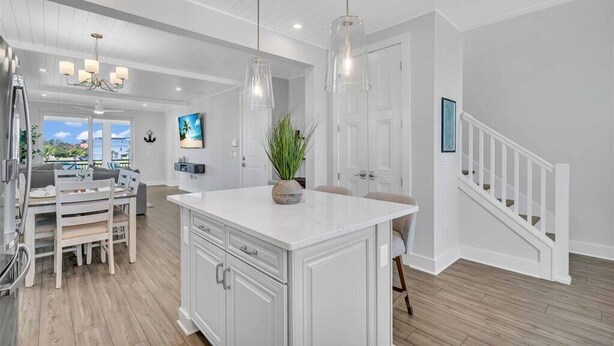 A modern kitchen with white cabinetry, a central island, and pendant lighting. - Bayview Pointe! Luxury Villa near Anna Maria Island with Saltwater Heated Pool! (Cortez)