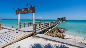 A wooden pier leading to Rod Reeler beach, with clear turquoise water and a boat docked at the end. - Bayview Pointe! Luxury Villa near Anna Maria Island with Saltwater Heated Pool! (Cortez)