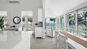 A modern kitchen with a large island, white cabinetry, and a view of the ocean.