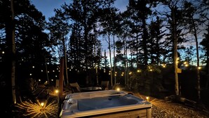 A hot tub in a forested area with string lights.