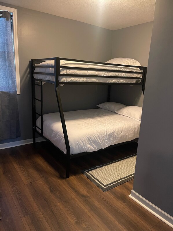 A bunk bed in a room with wooden flooring and a small rug.