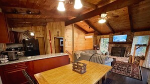 A cozy cabin interior with a wooden dining table, kitchen area, and a living space with a fireplace. - Pet Friendly Ski House, Game Rm, 4 Mins to Mt Snow (Dover)