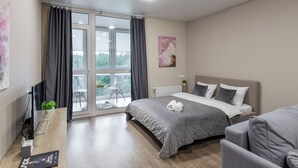 A modern bedroom with a large bed, a desk with a computer, and a view of the outdoors through a sliding glass door. - Apartments in the complex Vogue (Minsk)