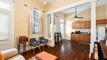 A spacious living room with a piano, a dining area, and a kitchen.