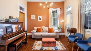 Un salon avec un piano, un canapé, un tapis et des fauteuils bleus.