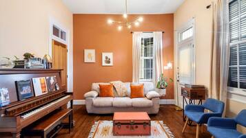 A living room with a piano, a sofa, a rug, and blue chairs.
