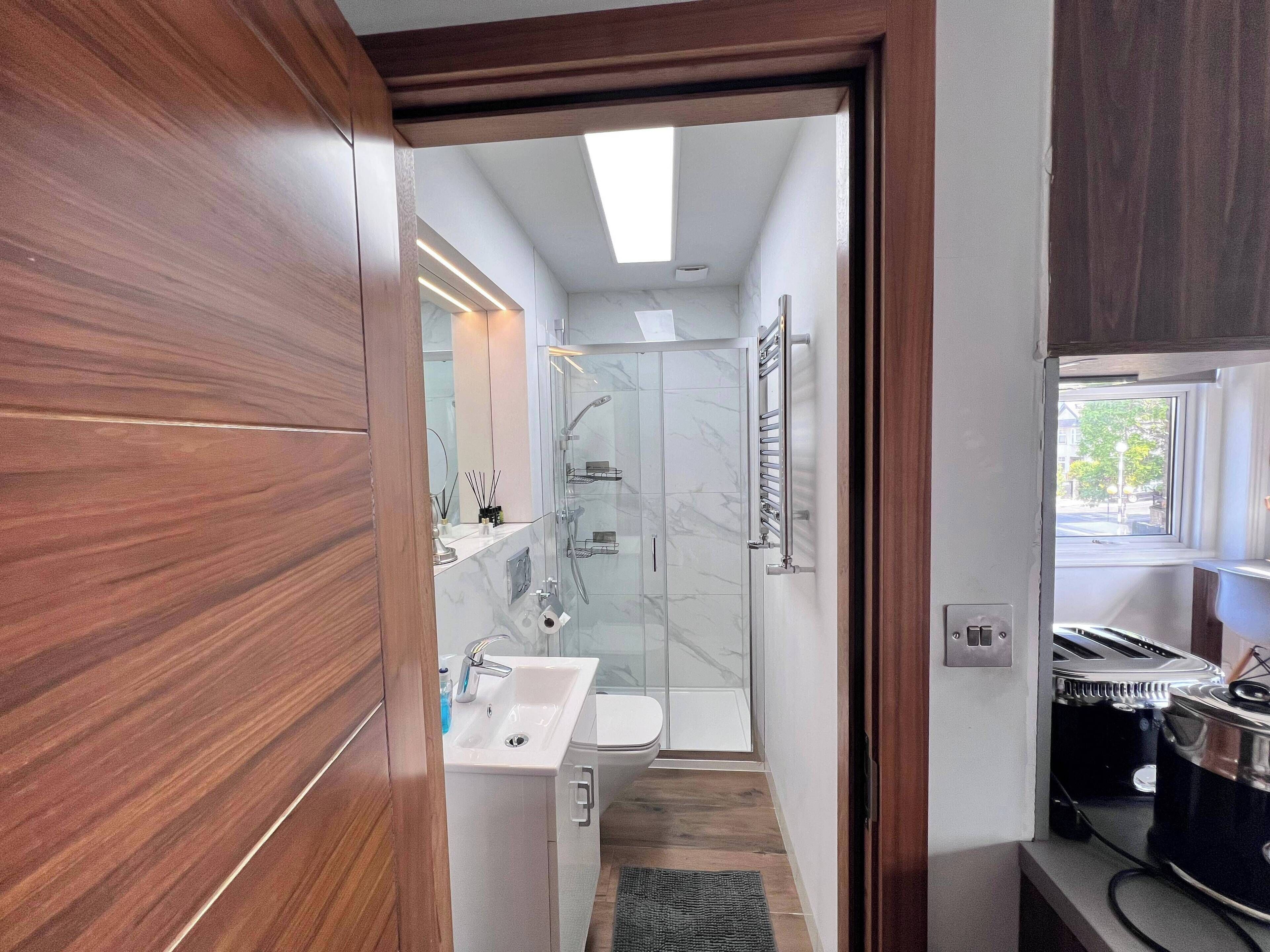 A modern bathroom with a glass shower, a sink, and a toilet.