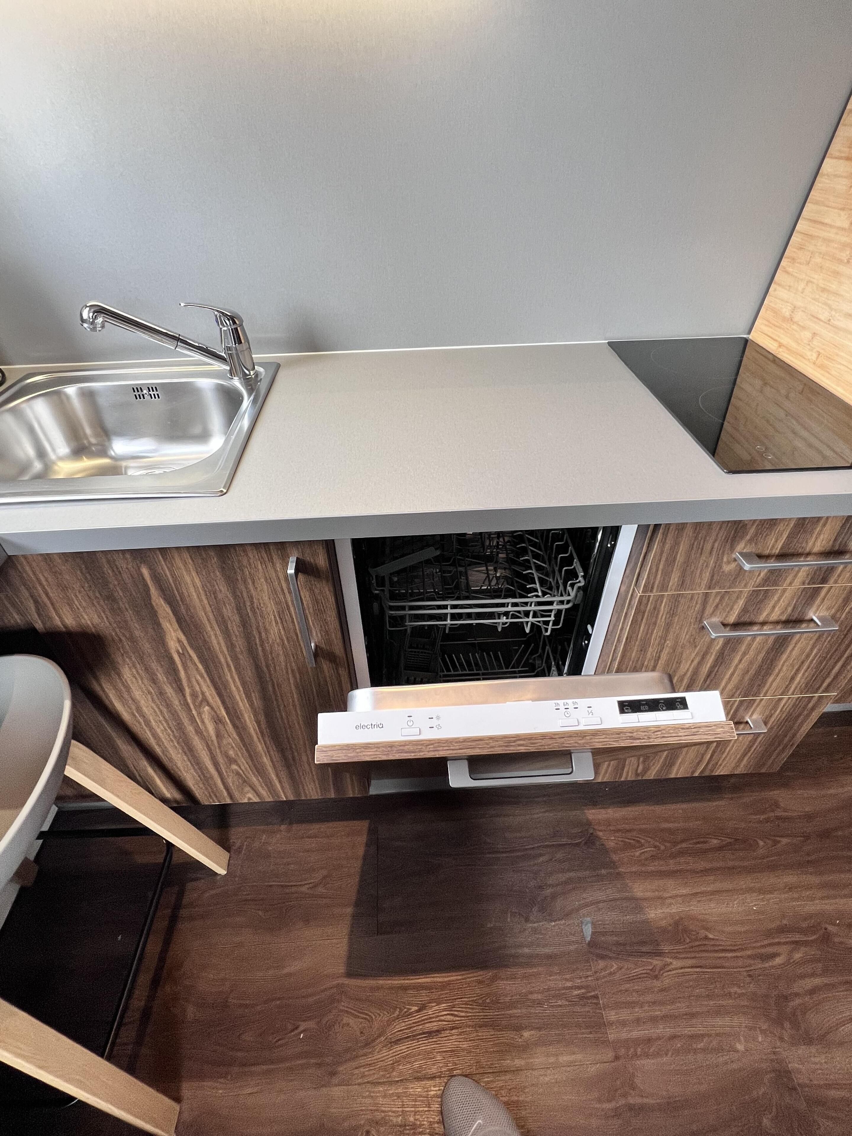 A modern kitchen with a stainless steel sink, wooden cabinets, and a built-in dishwasher.