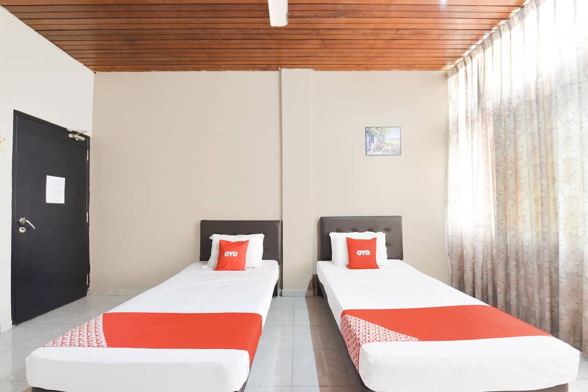 Une chambre d’hôtel avec deux lits, un plafond en bois, une porte noire et une fenêtre avec des rideaux.
