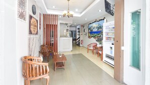 A hotel lobby with wooden furniture, a chandelier, a refrigerator, and a wall with a mural. - OYO 91052 Hotel Kenangan (Kuala Terengganu)