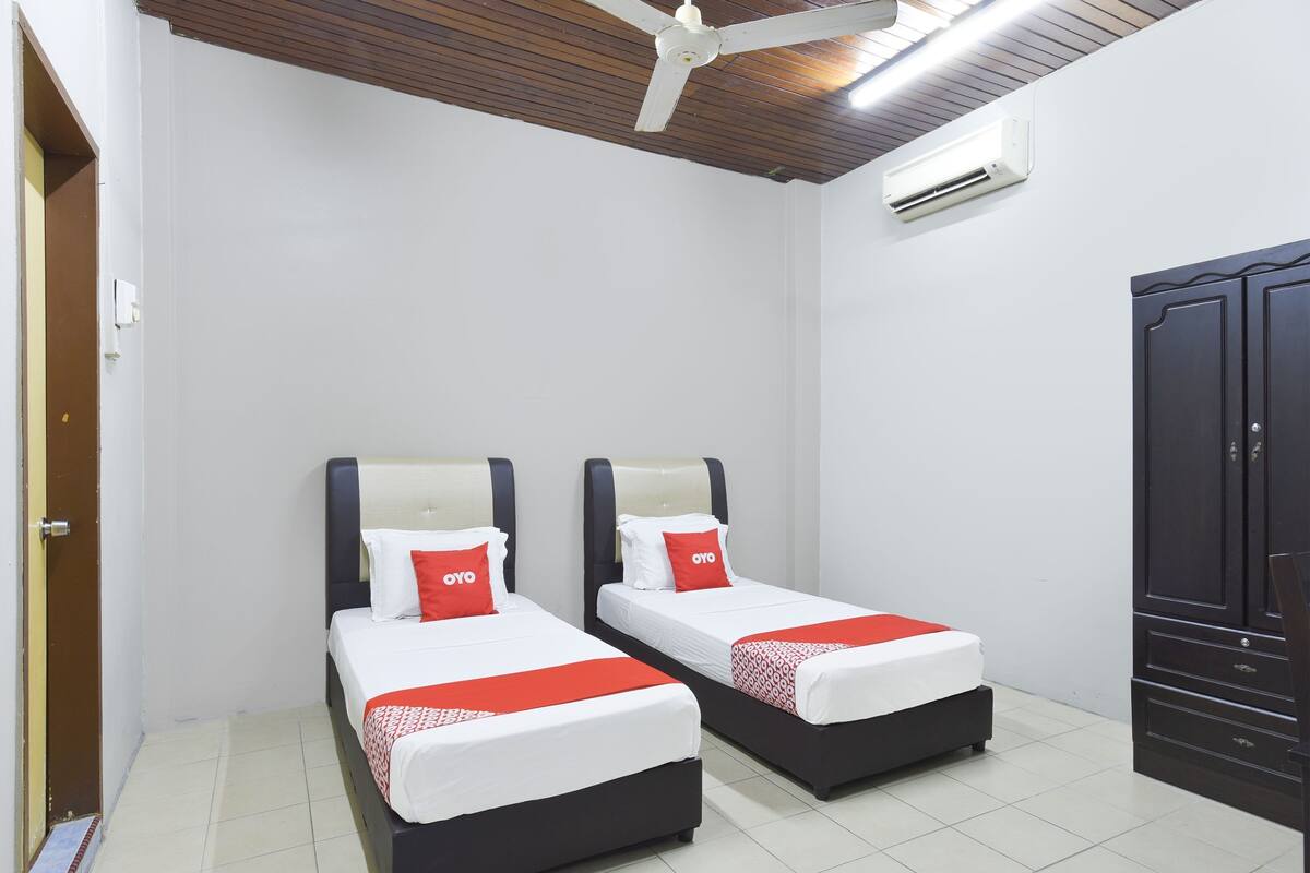 Une chambre avec deux lits, une armoire et un ventilateur de plafond.