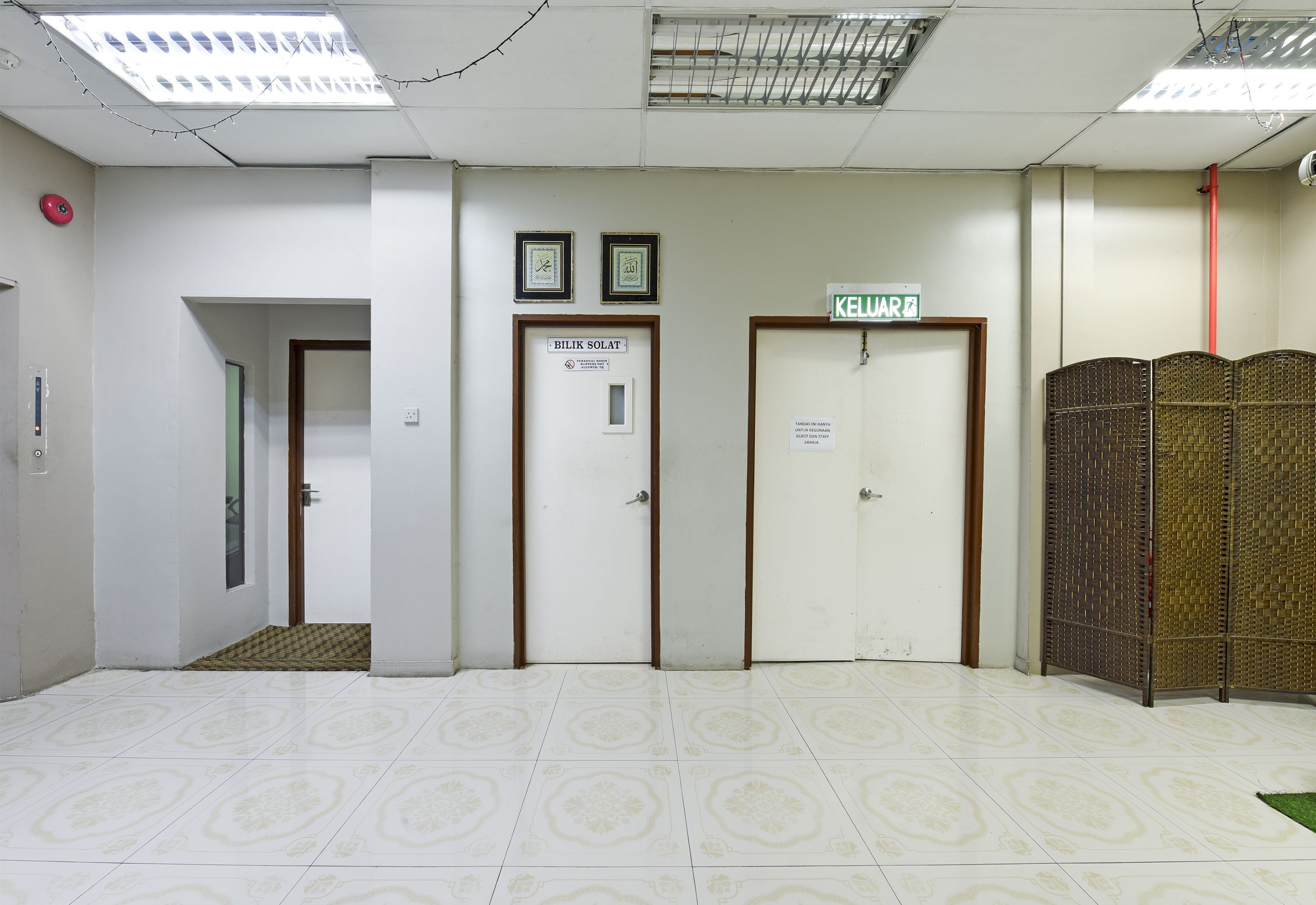 A hallway with three doors, one marked "BILIK SOLAT" and another with a sign indicating a "KELUAR."