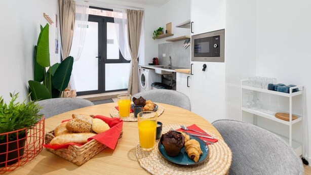 Una cocina compacta con microondas, un lavamanos y una ventana con cortinas.