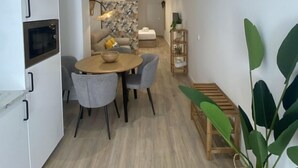 Una cocina moderna con armarios blancos, horno empotrado y comedor con mesa y sillas de madera.