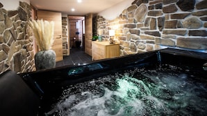 Een wellnessruimte met een jacuzzi, stenen muren en een houten kast.