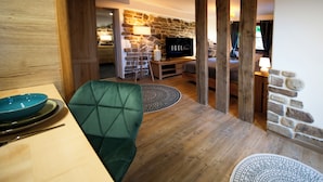 Een gezellige woonkamer met een stenen muur, een televisie en een groene fauteuil.
