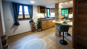 Een moderne keuken met houten kastjes, een stenen zuil en een bar met krukken.