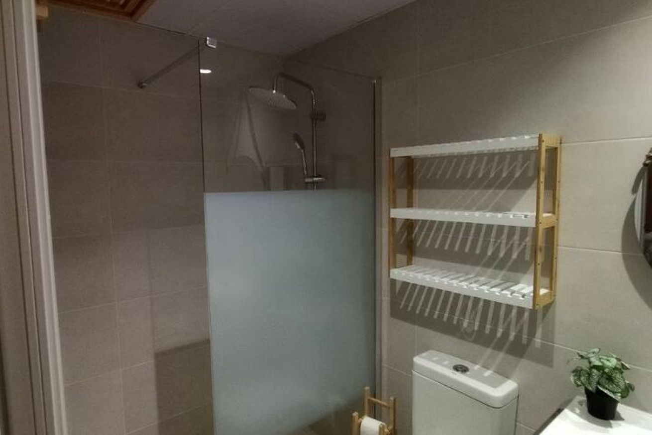 Une salle de bain moderne avec une douche à parois de verre, des toilettes et un petit lavabo.