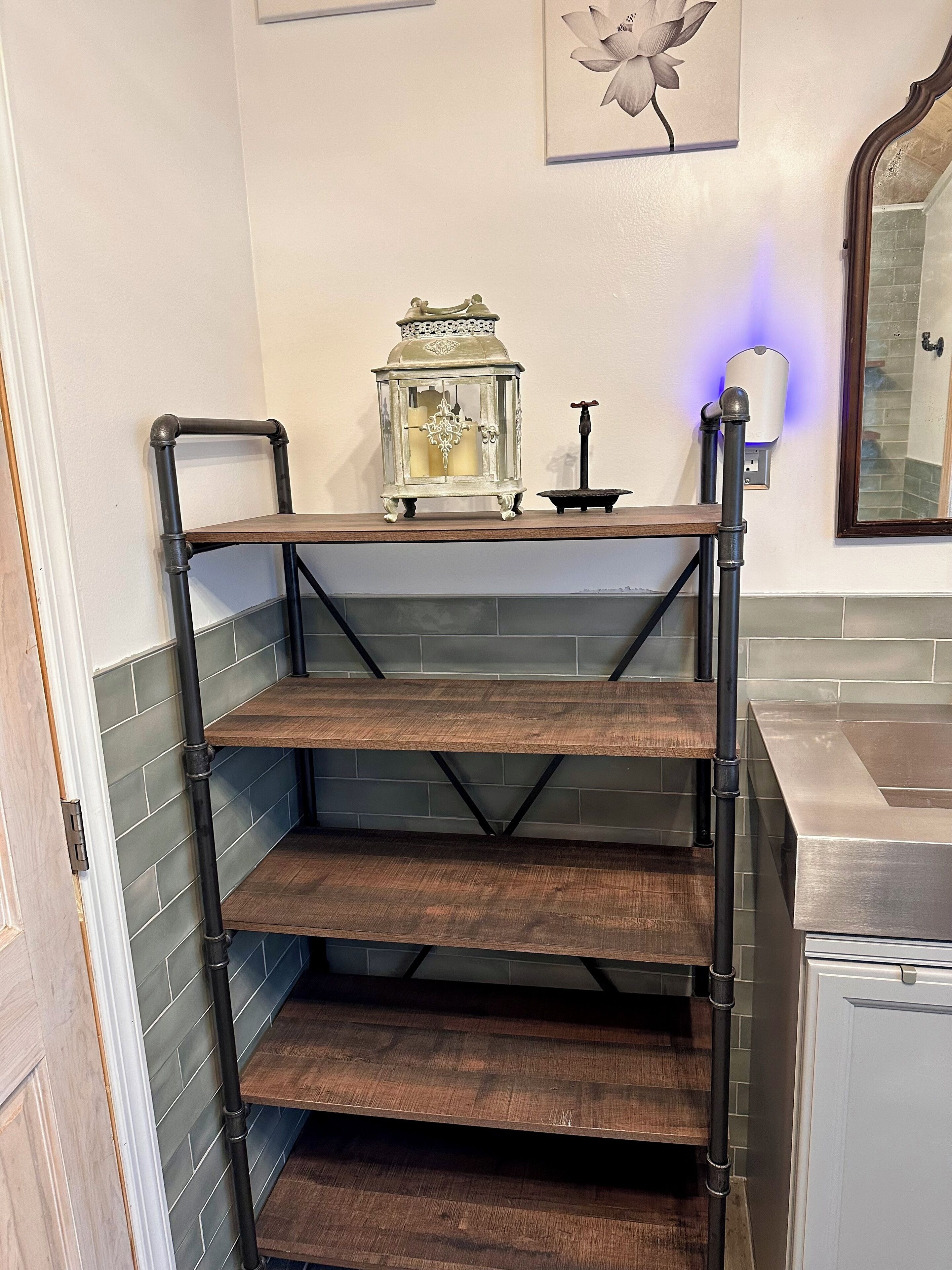 A kitchen with a wooden shelf unit, a decorative lantern, and a wall-mounted soap dispenser.