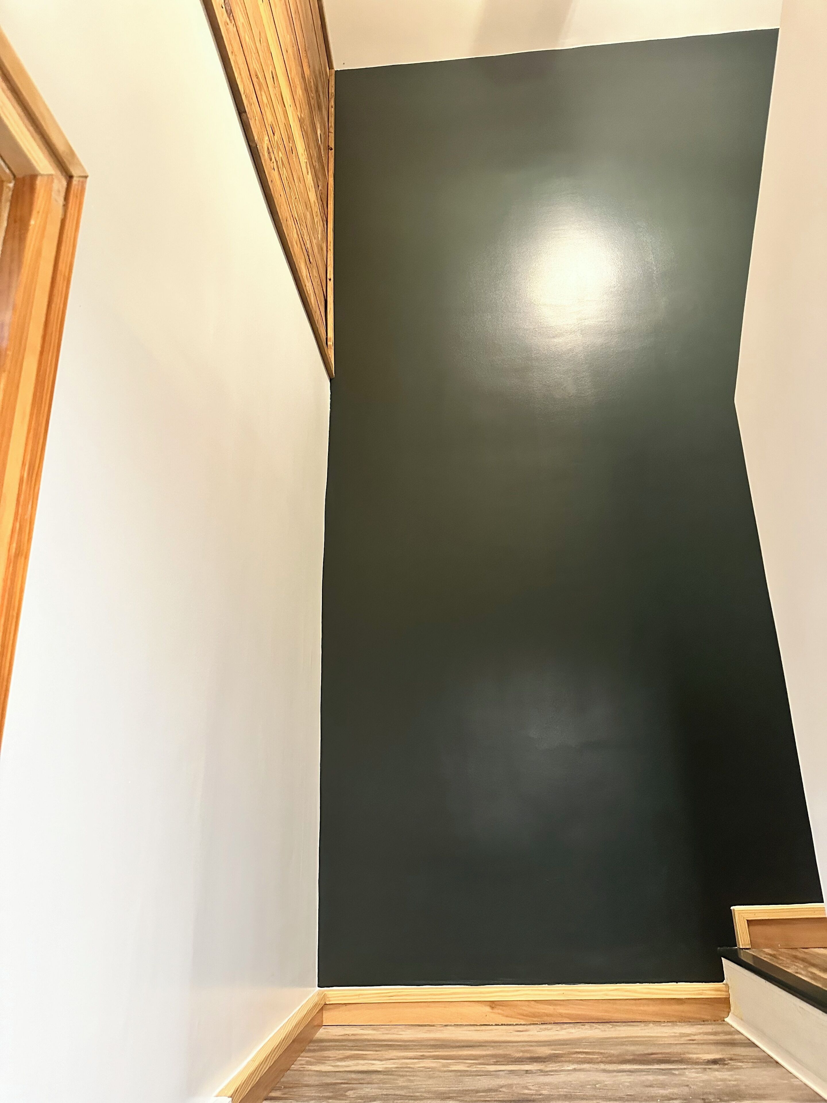 Ein Zimmer mit einer dunkel gefärbten Wand, Holzvertäfelung und Holzboden.
