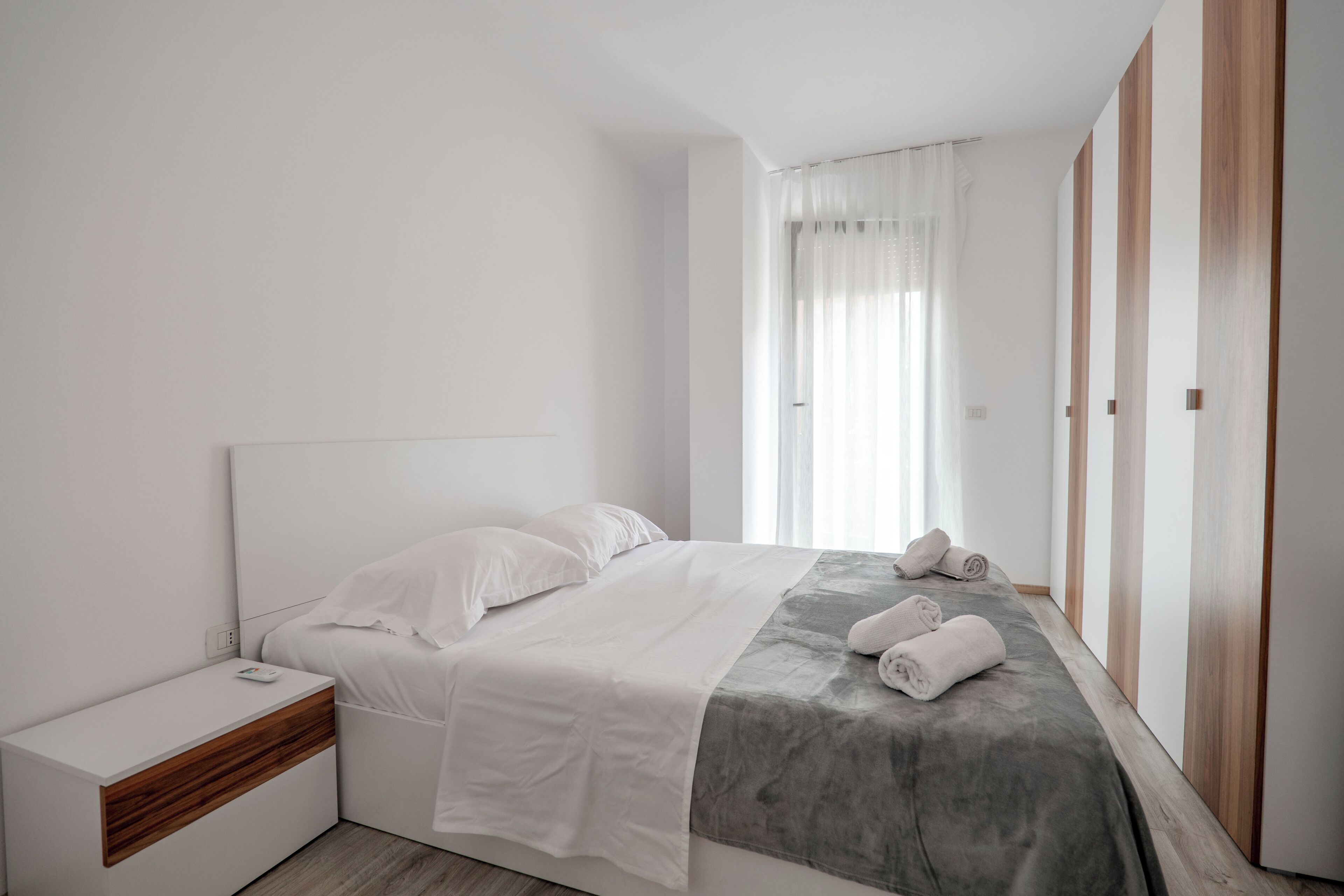 A modern bedroom with a bed, bedside table, and a wardrobe.