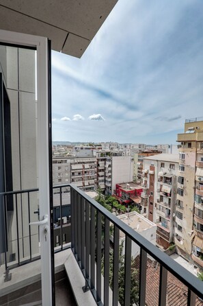 A balcony with a view of a residential area, including multi-story buildings and a red structure. - Kalpazo Tirana Mosaic (Tirana)
