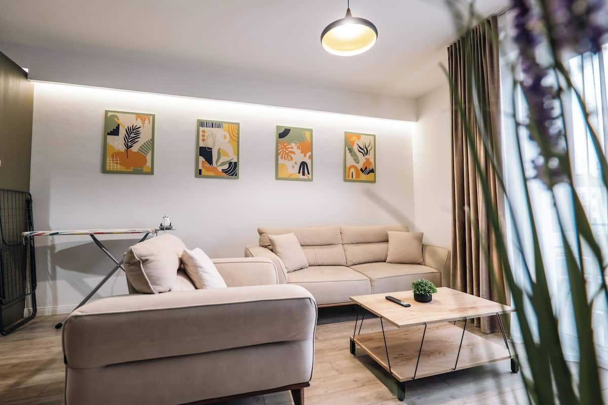 Un salon moderne avec un canapé, une table basse et un luminaire suspendu.