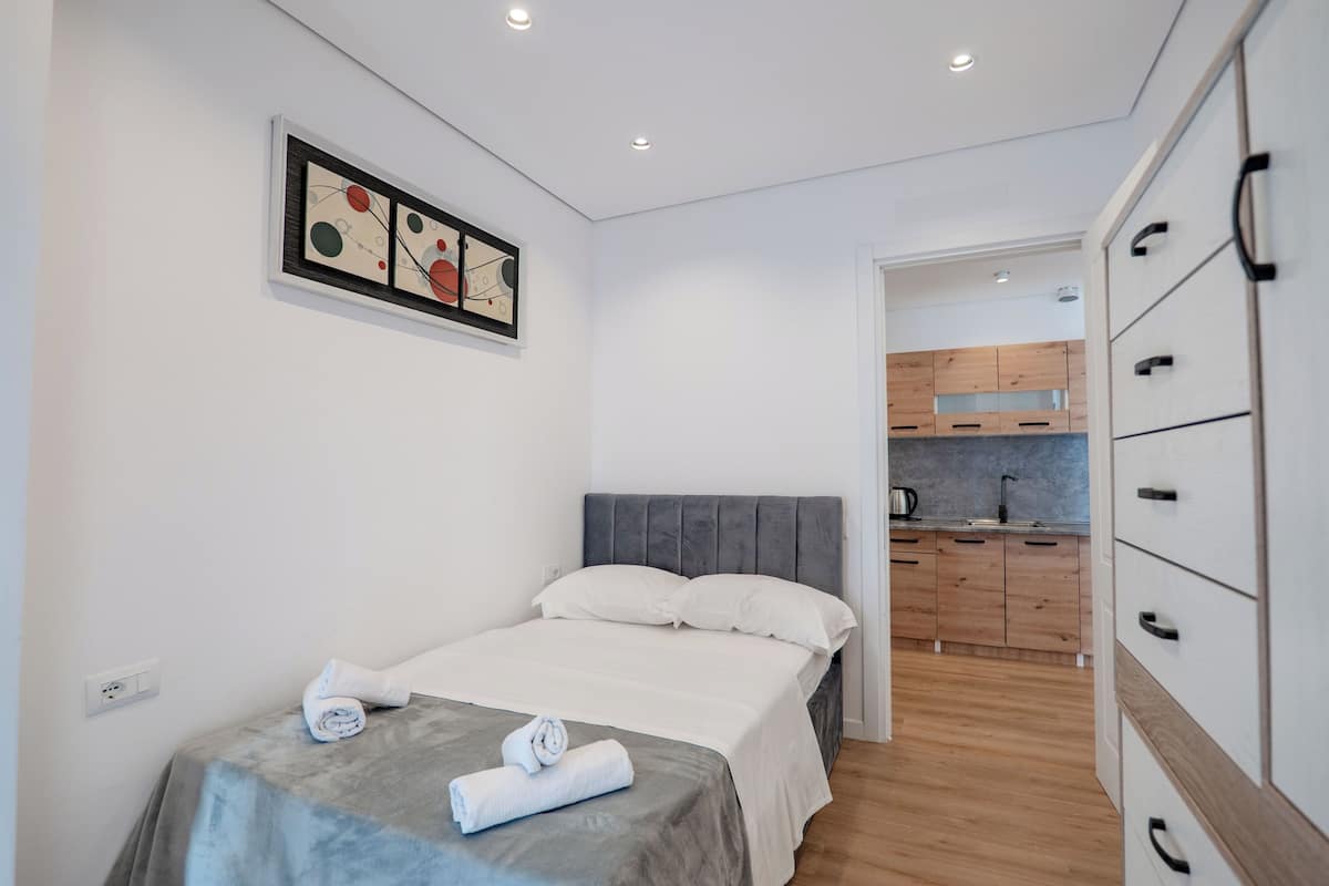 Une chambre à coucher avec un lit, un tableau et une vue sur la cuisine.
