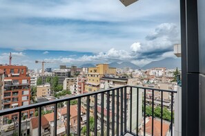A cityscape with buildings, a crane, and mountains in the distance. - Kalpazo Tirana Mosaic (Tirana)