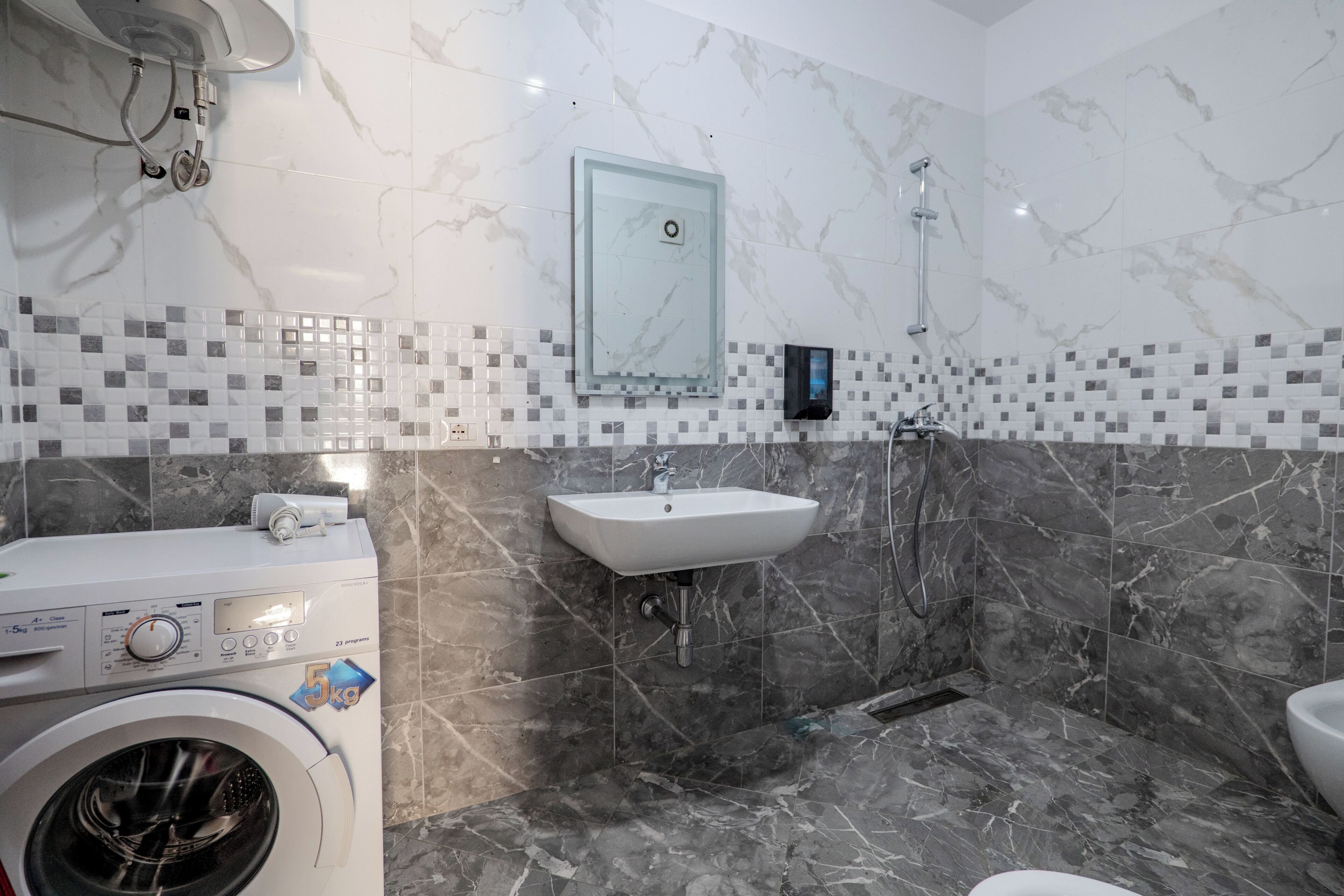 A bathroom with a washing machine, a sink, and a shower.