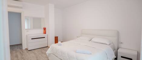A bedroom with a bed, bedside tables, a dresser, a mirror, and a ceiling light.
