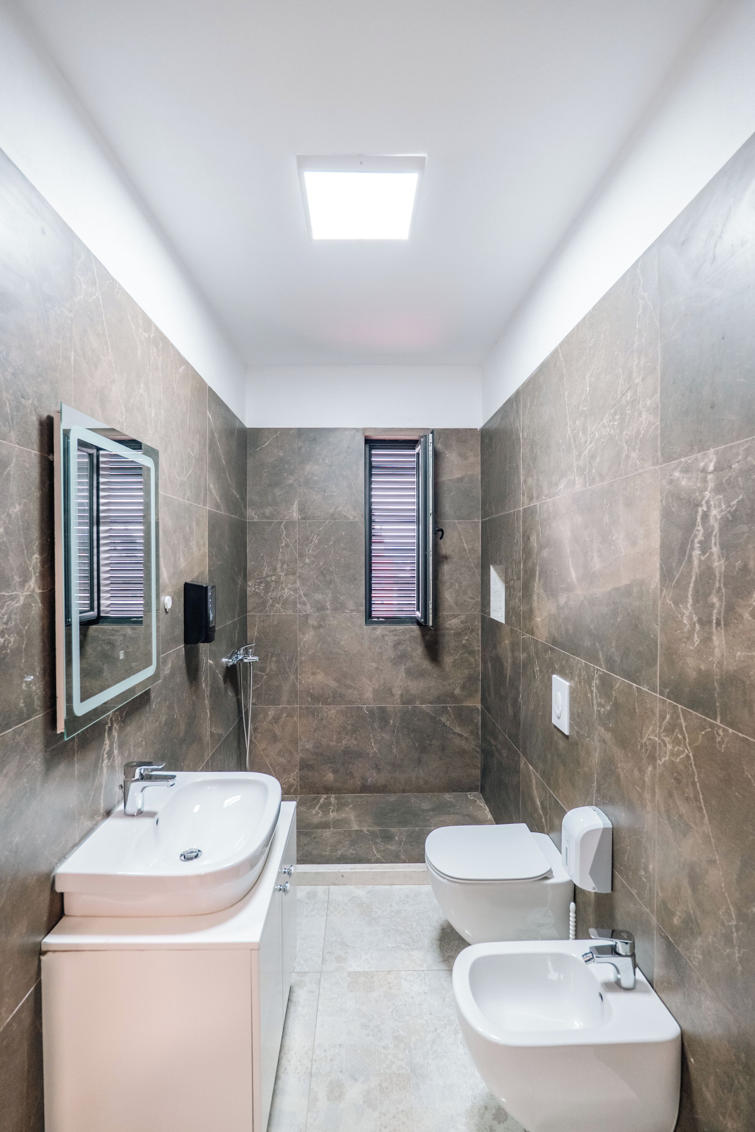 Un baño moderno con ducha, dos lavamanos y un bidé.
