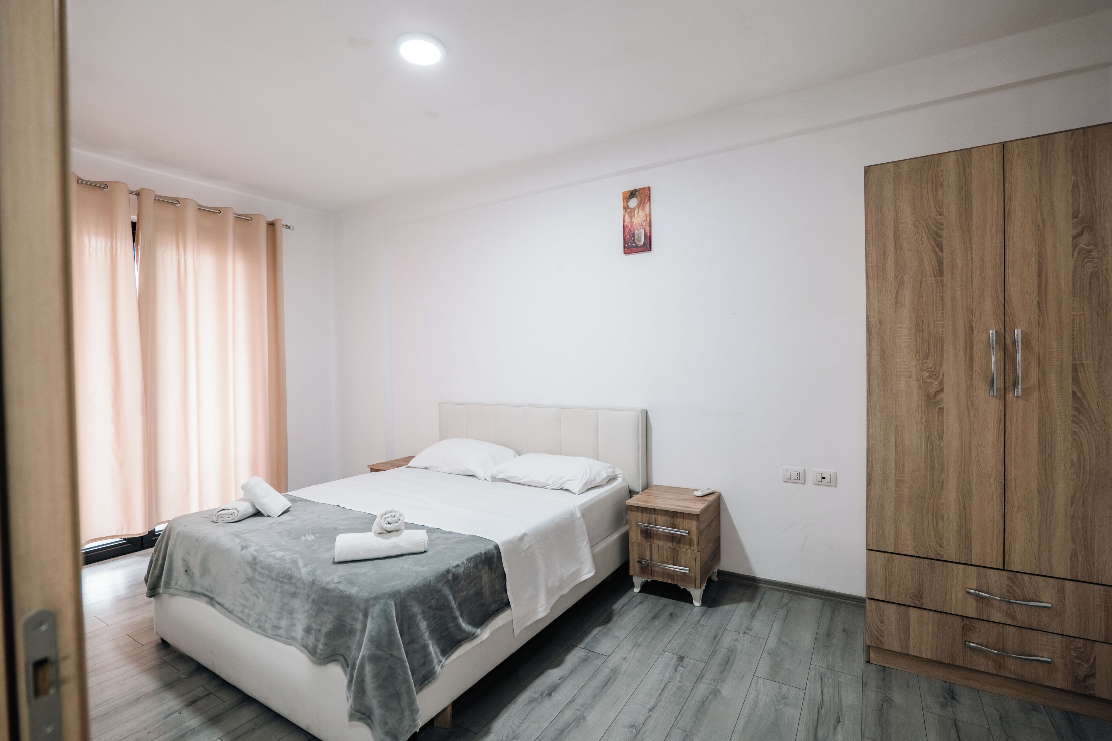 Une chambre à coucher avec un lit, une table de chevet, une armoire et une fenêtre avec des rideaux.