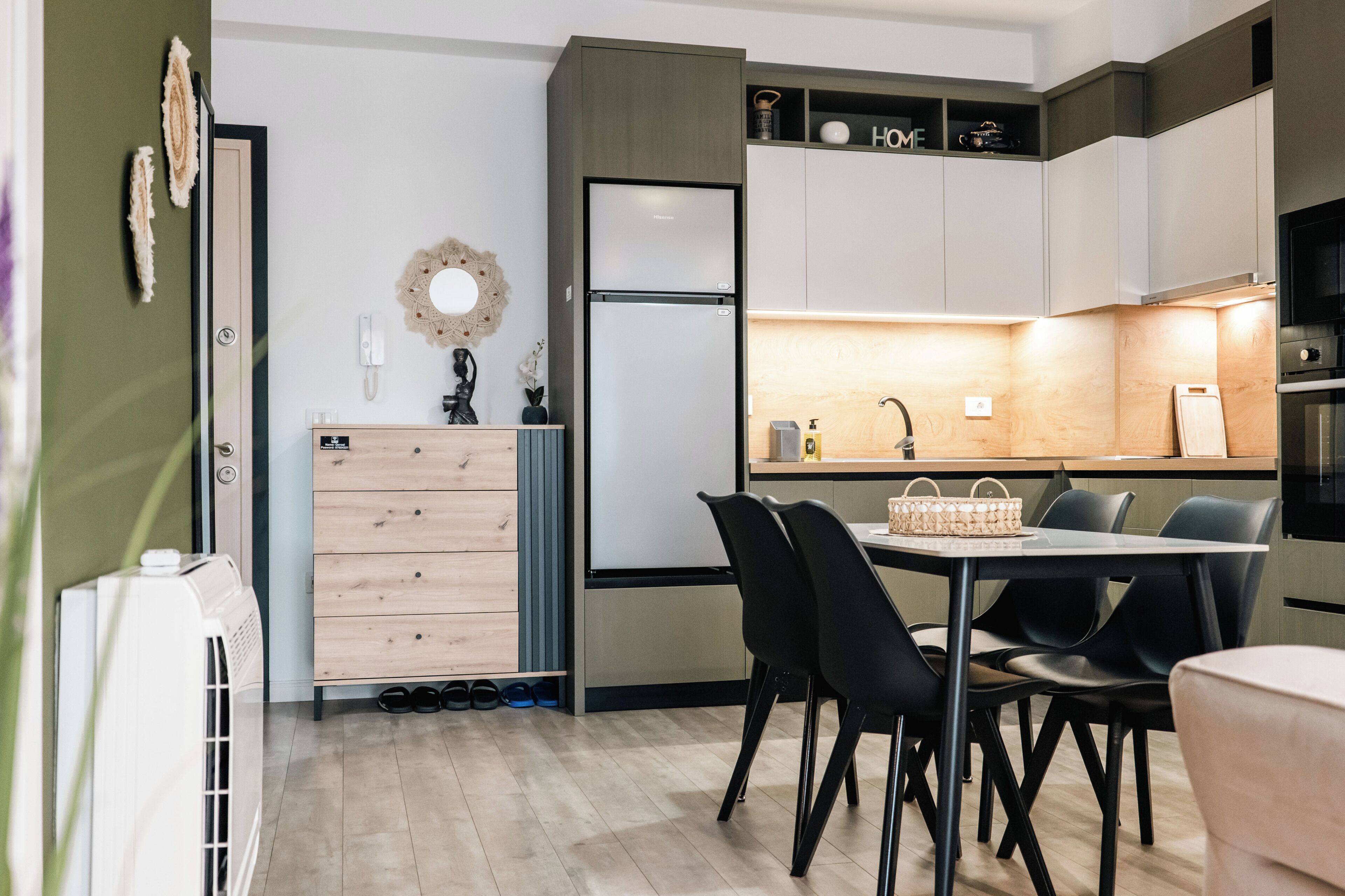 Une cuisine moderne dotée d’un réfrigérateur encastré, de meubles de rangement en bois, d’une table à manger avec des chaises et d’un petit îlot central avec un évier.