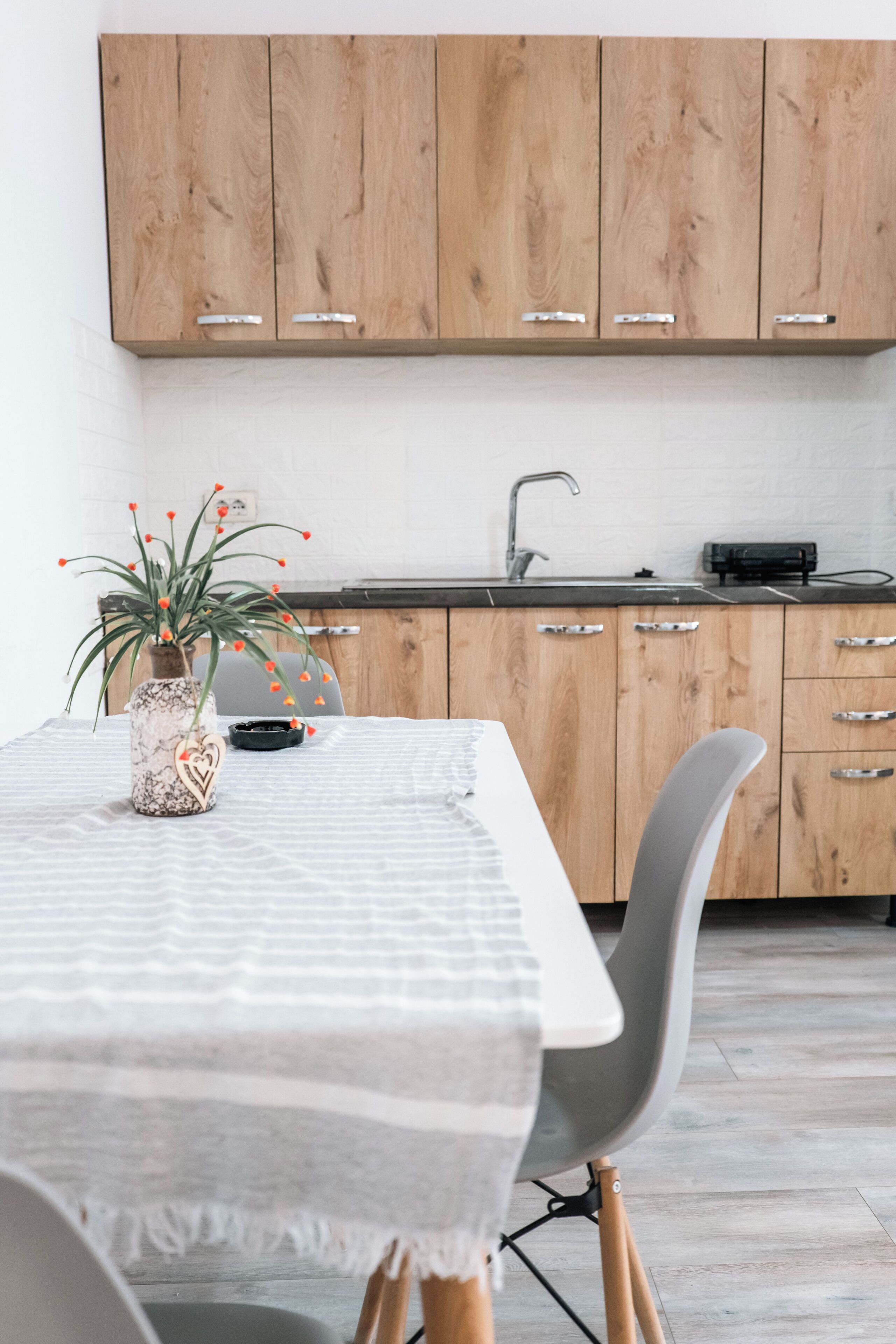 A kitchen with wooden cabinets, a sink, and a table with a white tablecloth.