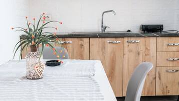 A kitchen with wooden cabinets, a sink, and a table with a white tablecloth.
