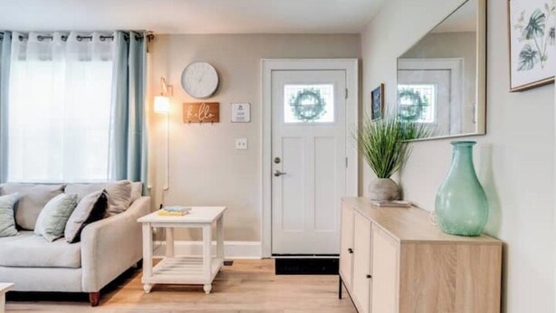 Een woonkamer met een bank, een bijzettafeltje, een kast en een deur versierd met een krans.