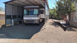 A covered RV parking area with a Simba camper parked inside. - Vigilante Inn Covered Wagon (Tombstone)