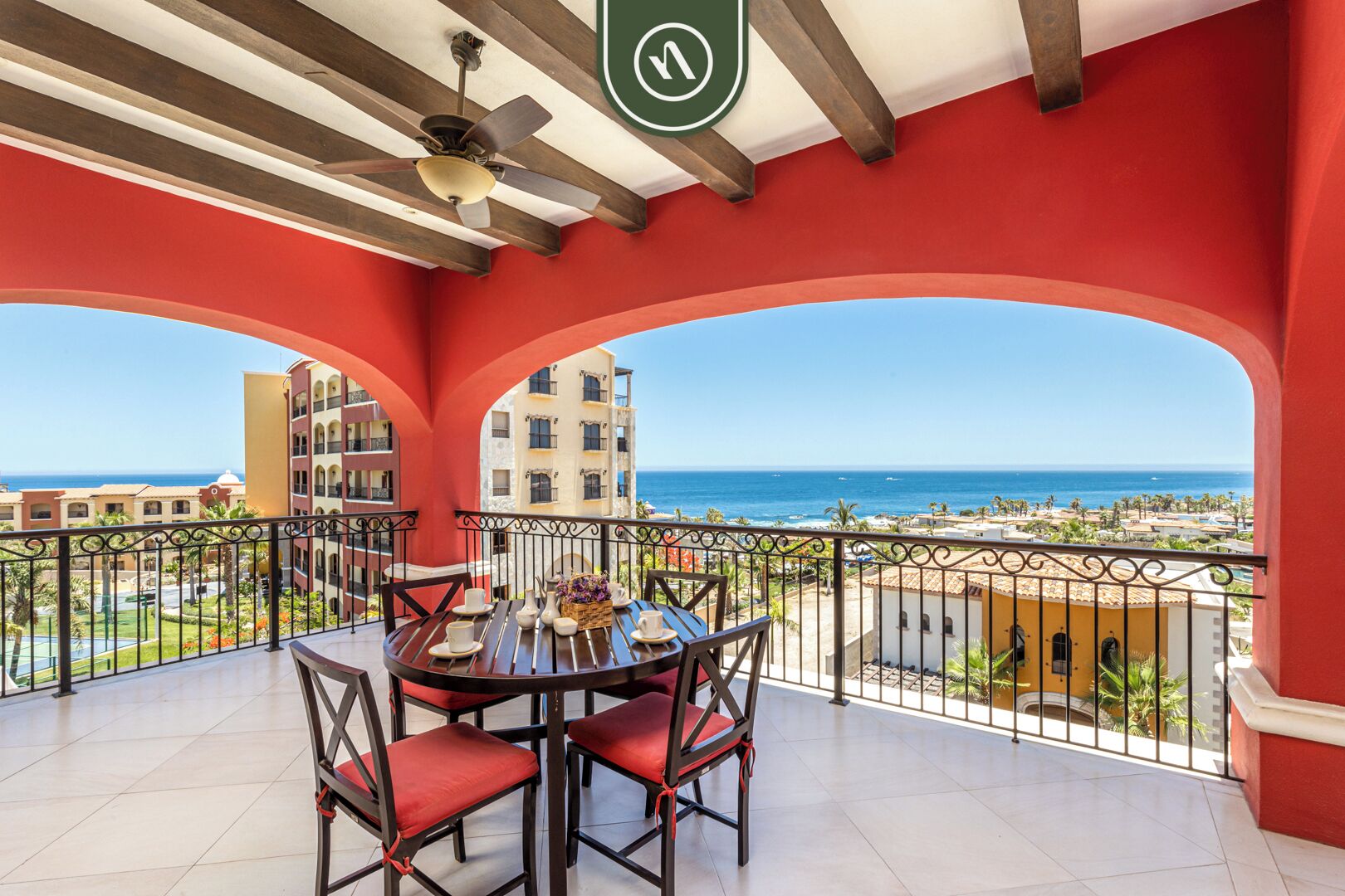 Ein Balkon mit Esstisch, mit Blick auf die Küste, Gebäude und das Meer.
