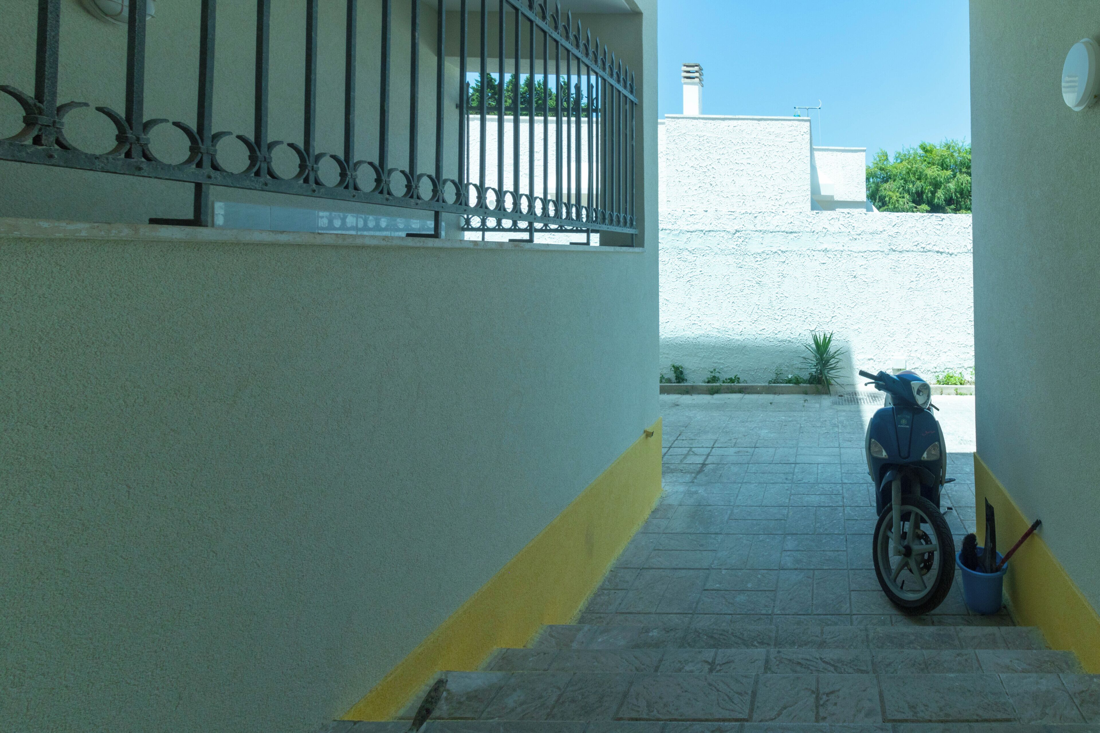 Una escalera estrecha que conduce a un espacio cubierto donde se encuentra estacionada una motocicleta.