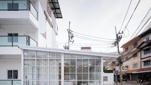 Un bâtiment moderne avec une façade en verre, une terrasse en bois et une enseigne indiquant qu’il s’agit d’un hôtel.