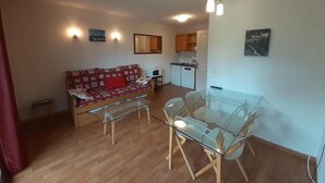 A compact living space with a sofa, a glass dining table, and a kitchenette in the background. - 180m from ski lifts, floor -2, balcony, tv, ski locker, 37m², Valfréjus (Valfréjus)