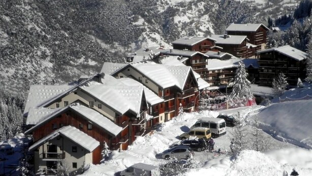 A snow-covered lodge with multiple buildings, a ski slope in the background, and a few parked cars. - Ski-in/ski-out & foot of the slopes, 3rd floor, balcony, tv, ski locker, 28m², Valfréjus (Valfréjus)