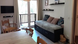 A bedroom with a bed, a TV, a dining table, chairs, a balcony, and a window with curtains. - Ski-in/ski-out & foot of the slopes, 3rd floor, balcony, tv, ski locker, 28m², Valfréjus (Valfréjus)