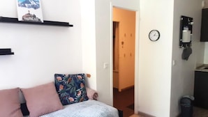 A small, well-lit room with a sofa, a clock on the wall, and a door leading to another room. - Ski-in/ski-out & foot of the slopes, 3rd floor, balcony, tv, ski locker, 28m², Valfréjus (Valfréjus)